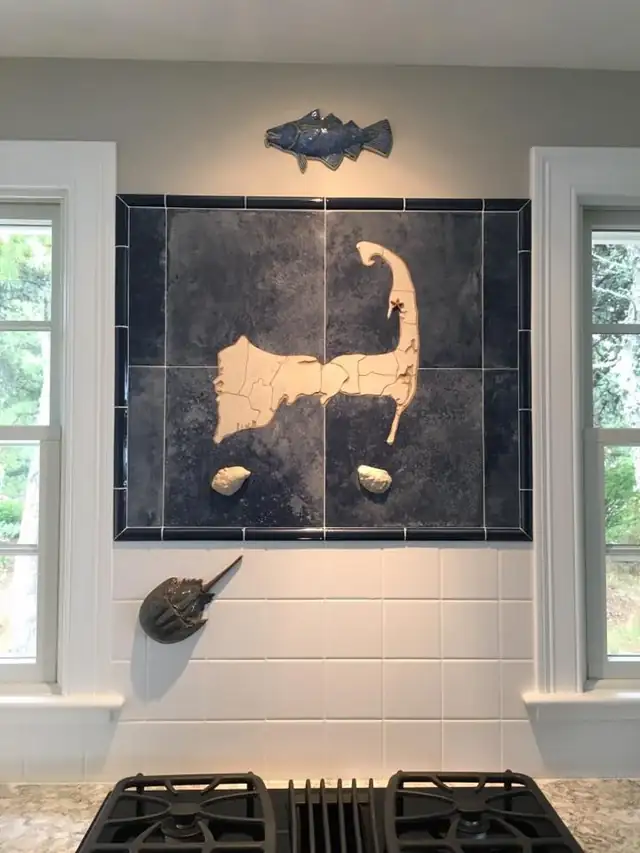 Tile mural of a cream Cape Cod map on deep blue tile above a white subway tile wall